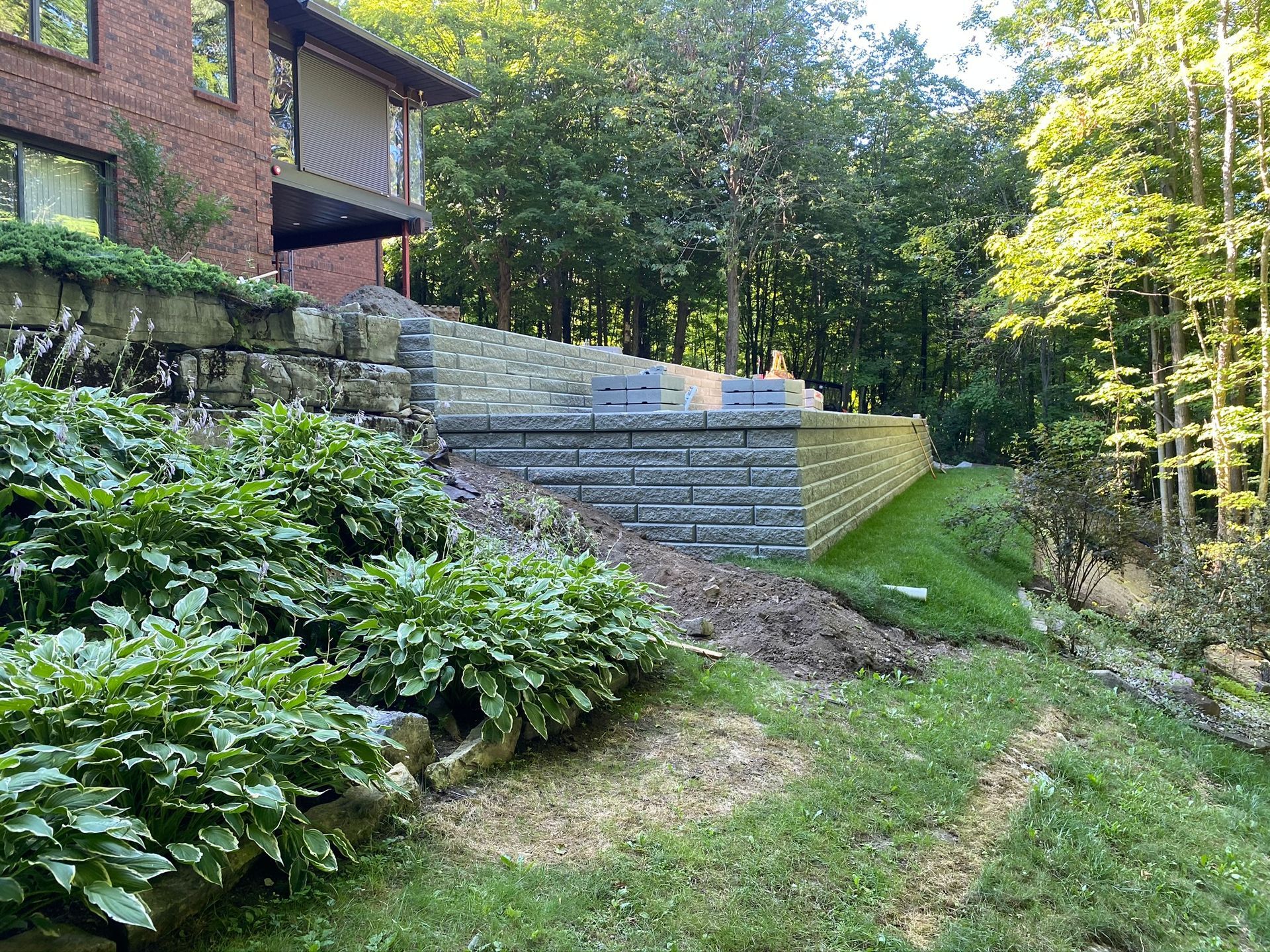 a stone wall is being built in the backyard of a house