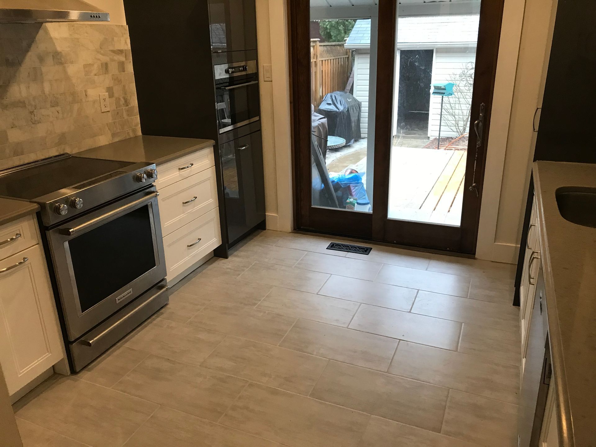 a kitchen with a stove , oven , refrigerator and sliding glass doors .