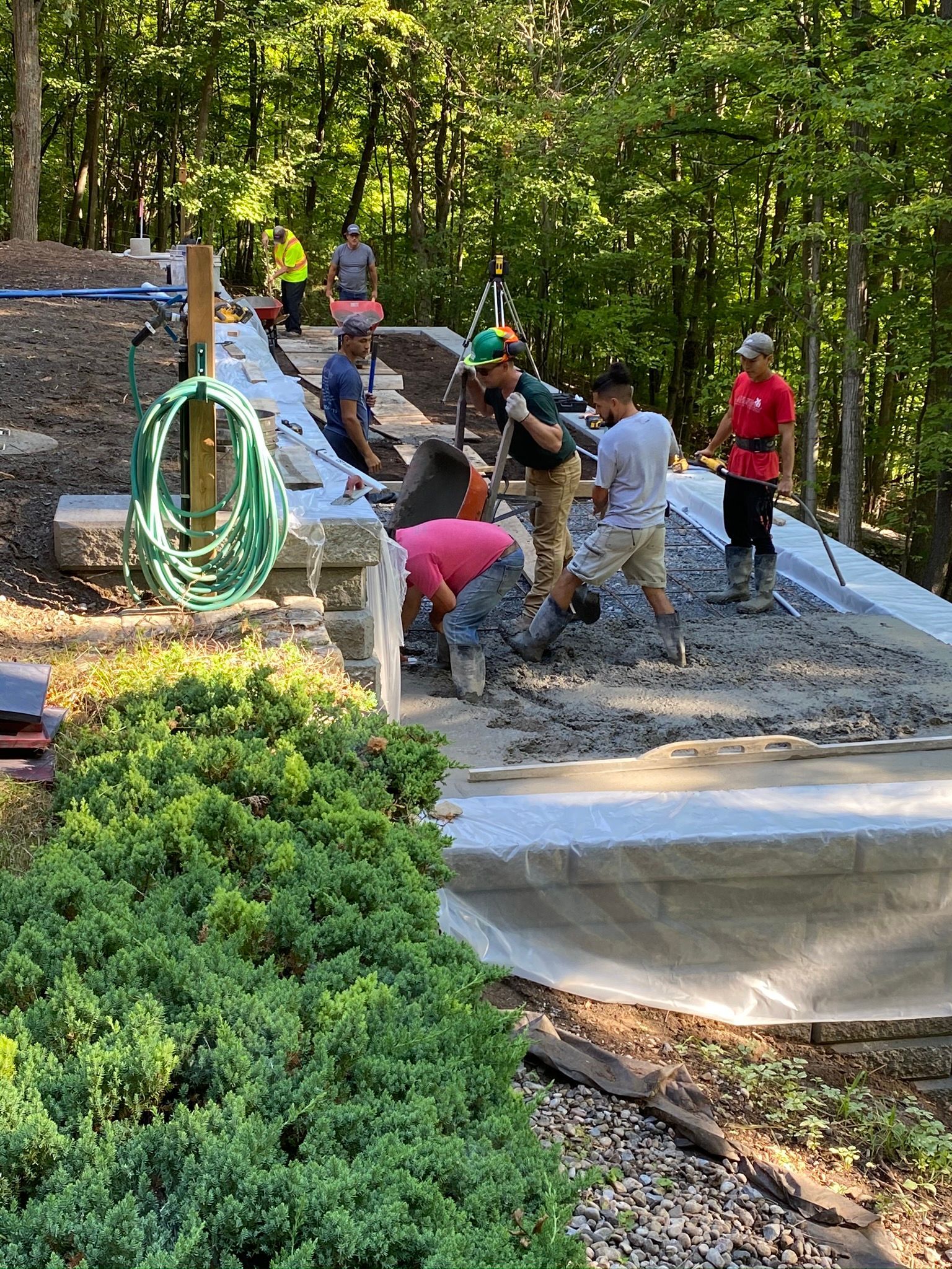 a group of men are working on a concrete walkway in the woods .