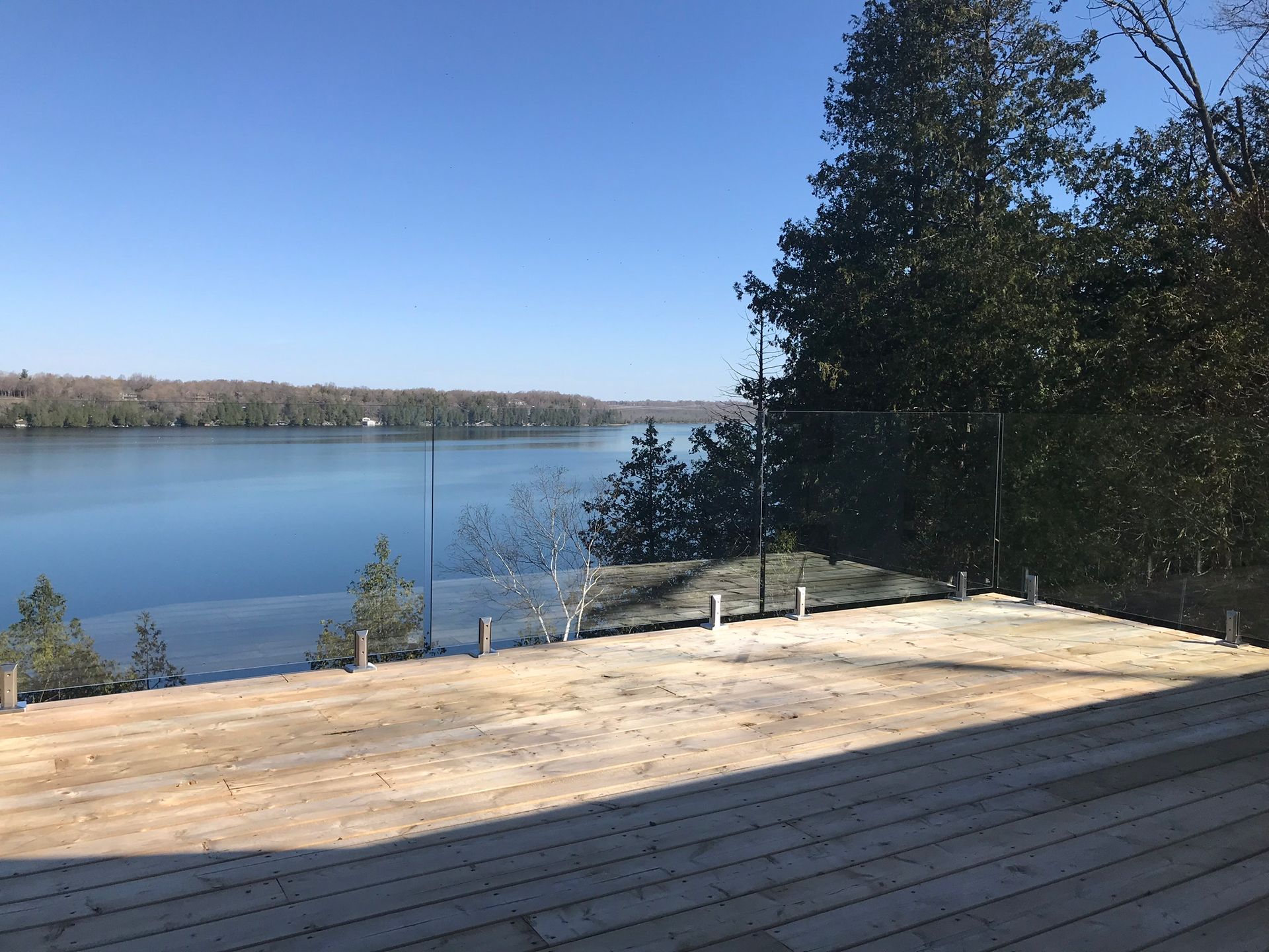 a wooden deck overlooking a lake with a glass railing