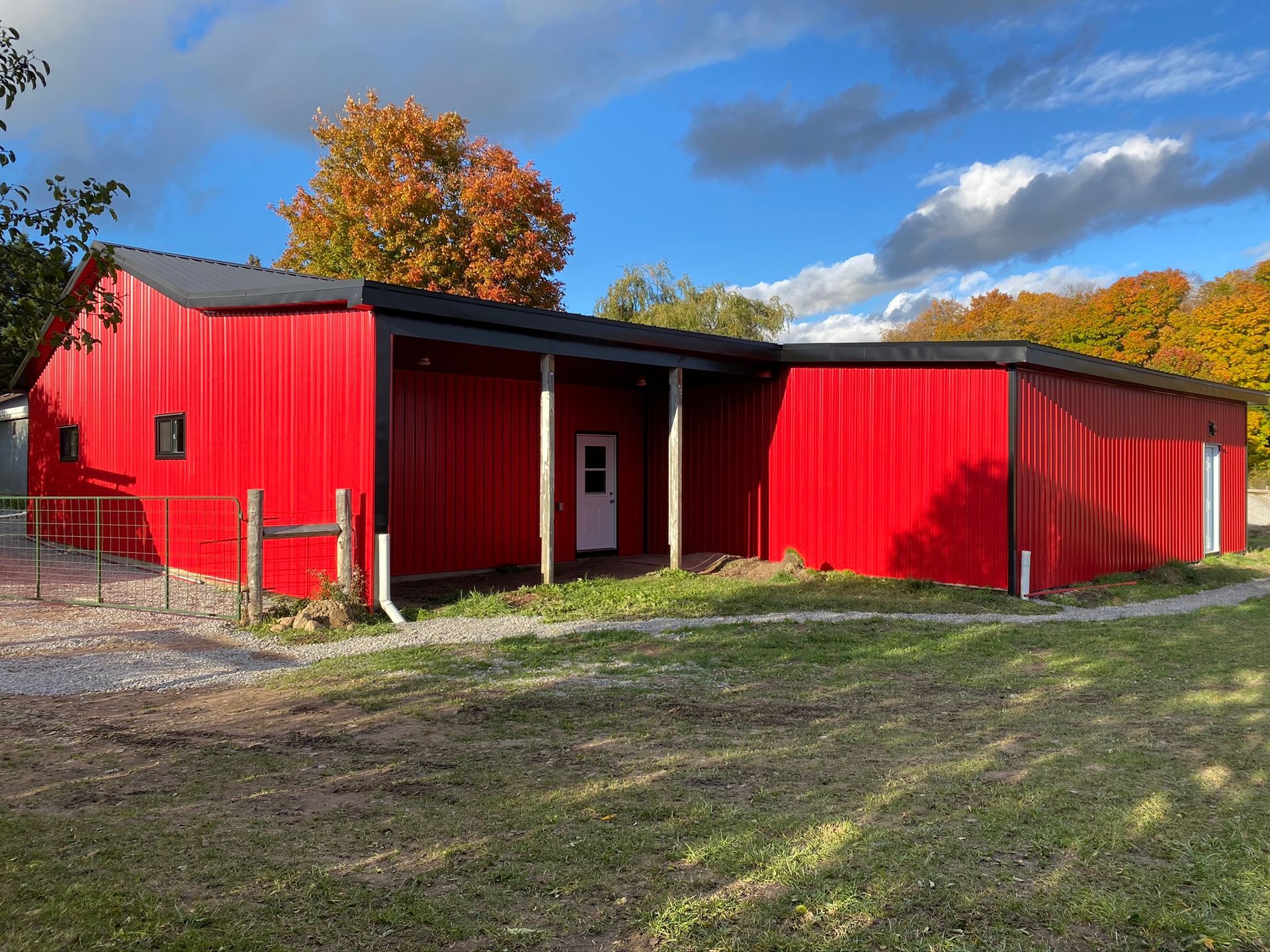 a large red barn is sitting in the middle of a grassy field .