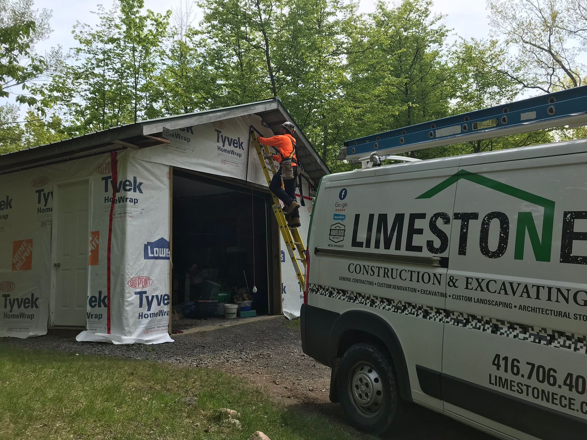 a man is standing on a ladder next to a limestone construction van .