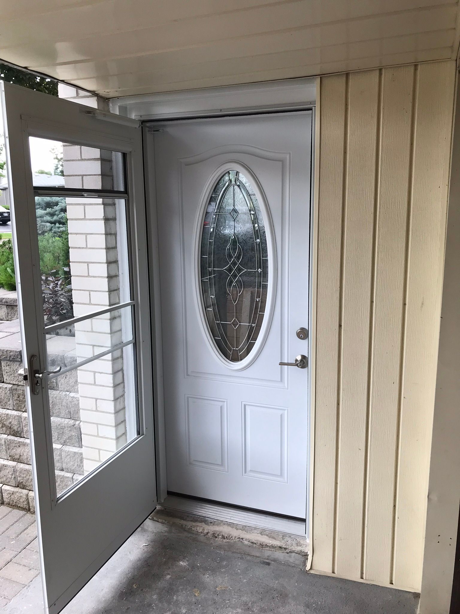 a white door with a glass window is open to a porch .