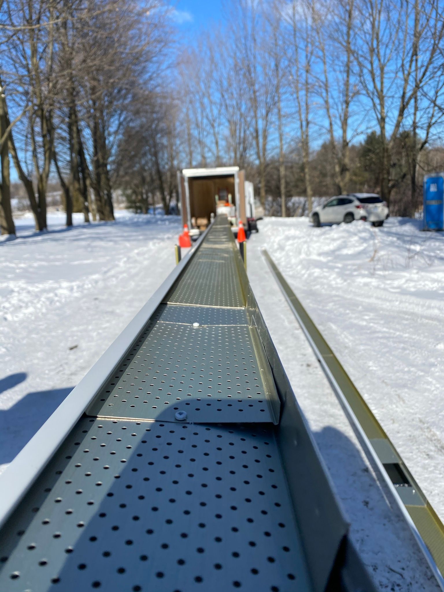 a conveyor belt in the snow with a truck in the background
