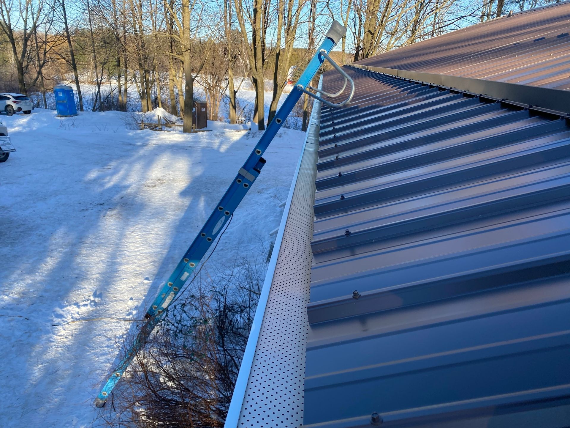 a gutter is hanging from the side of a building in the snow .