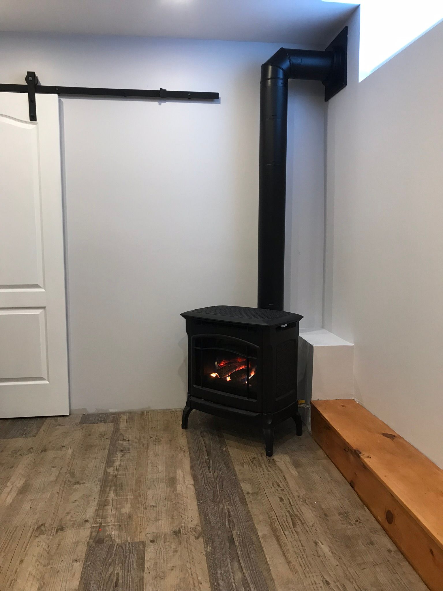 a wood stove is sitting in a room next to a sliding barn door .