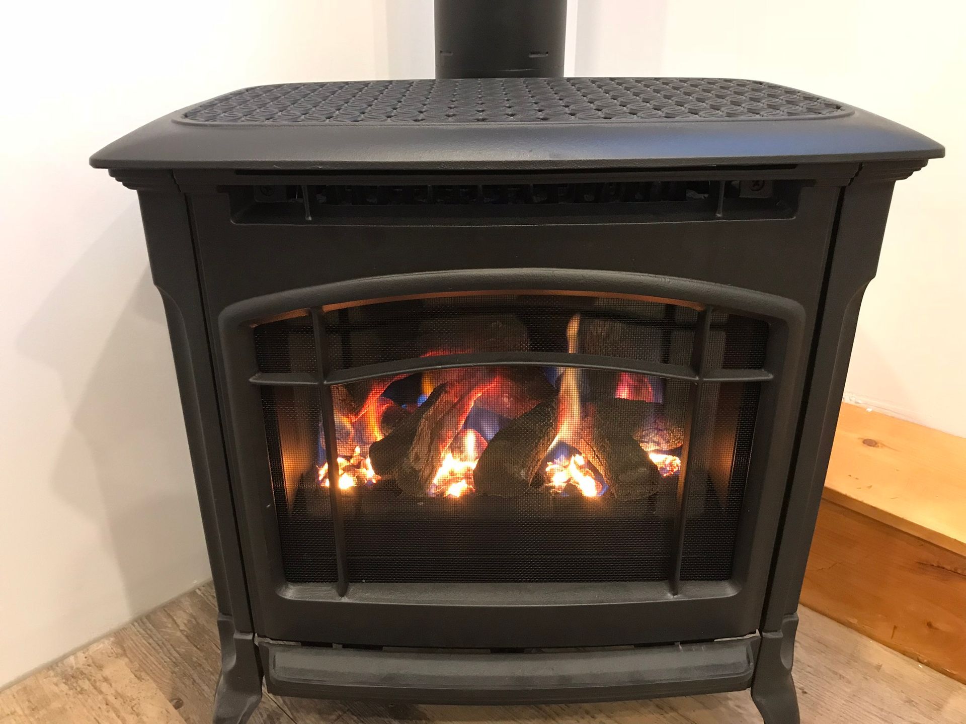 a gas fireplace is sitting on a wooden floor in a room .