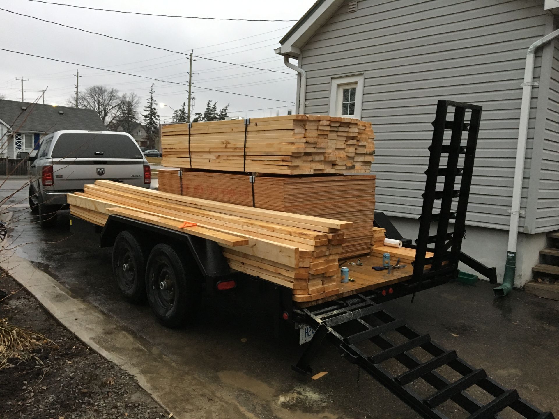 a trailer full of wood is parked in front of a house