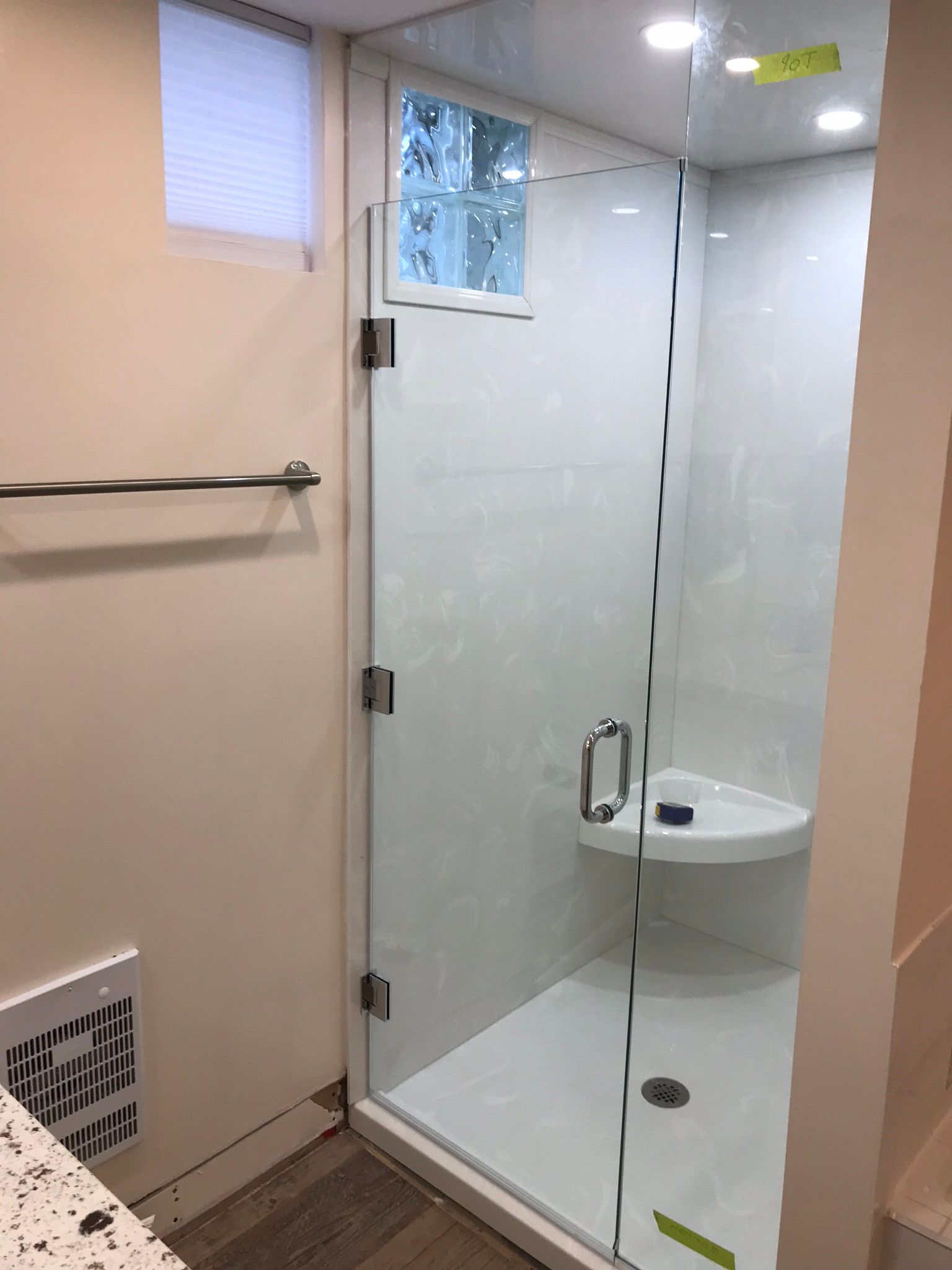 a bathroom with a walk in shower with a glass door and a window .