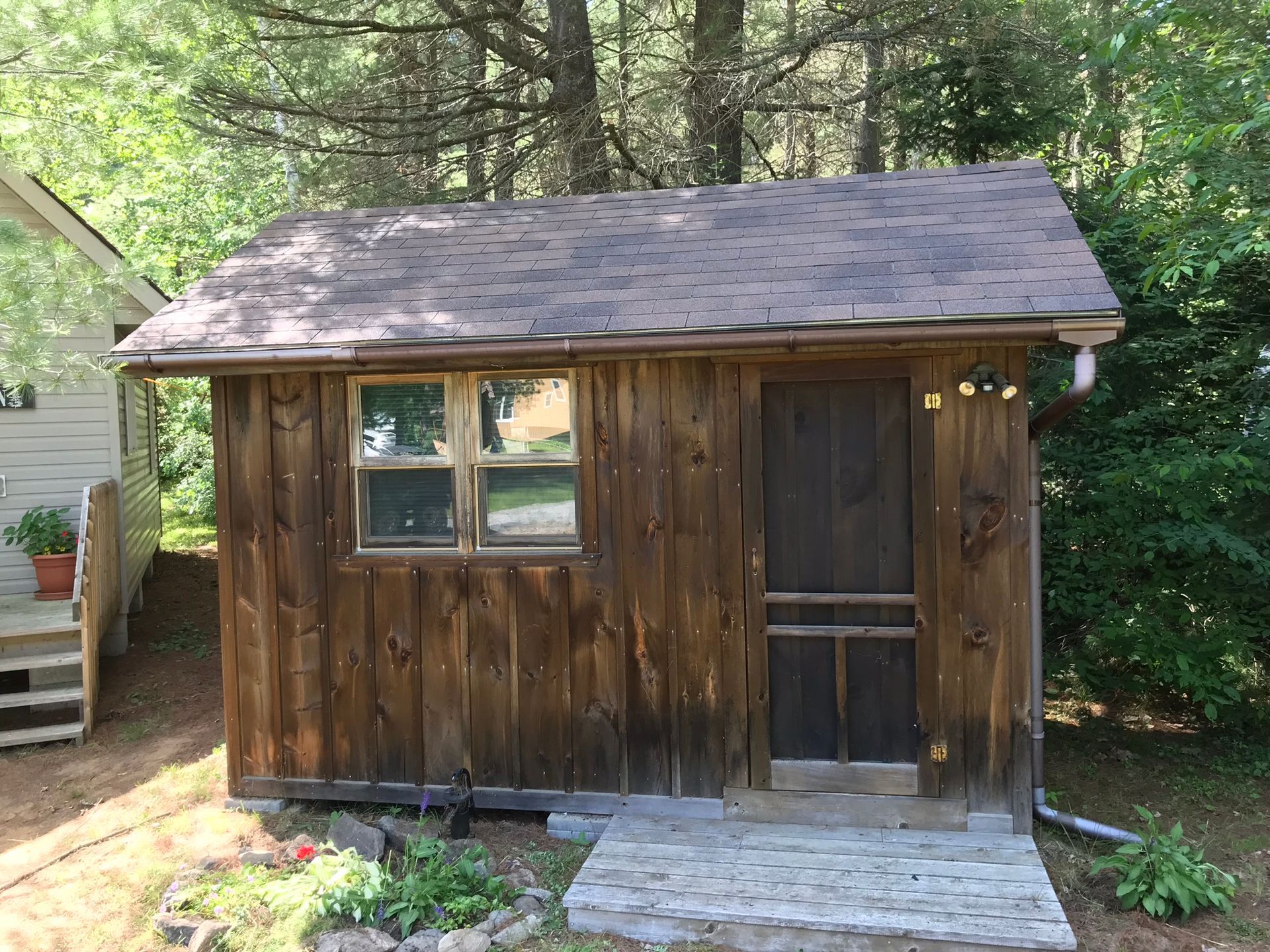 a small wooden shed with a screen door and a window