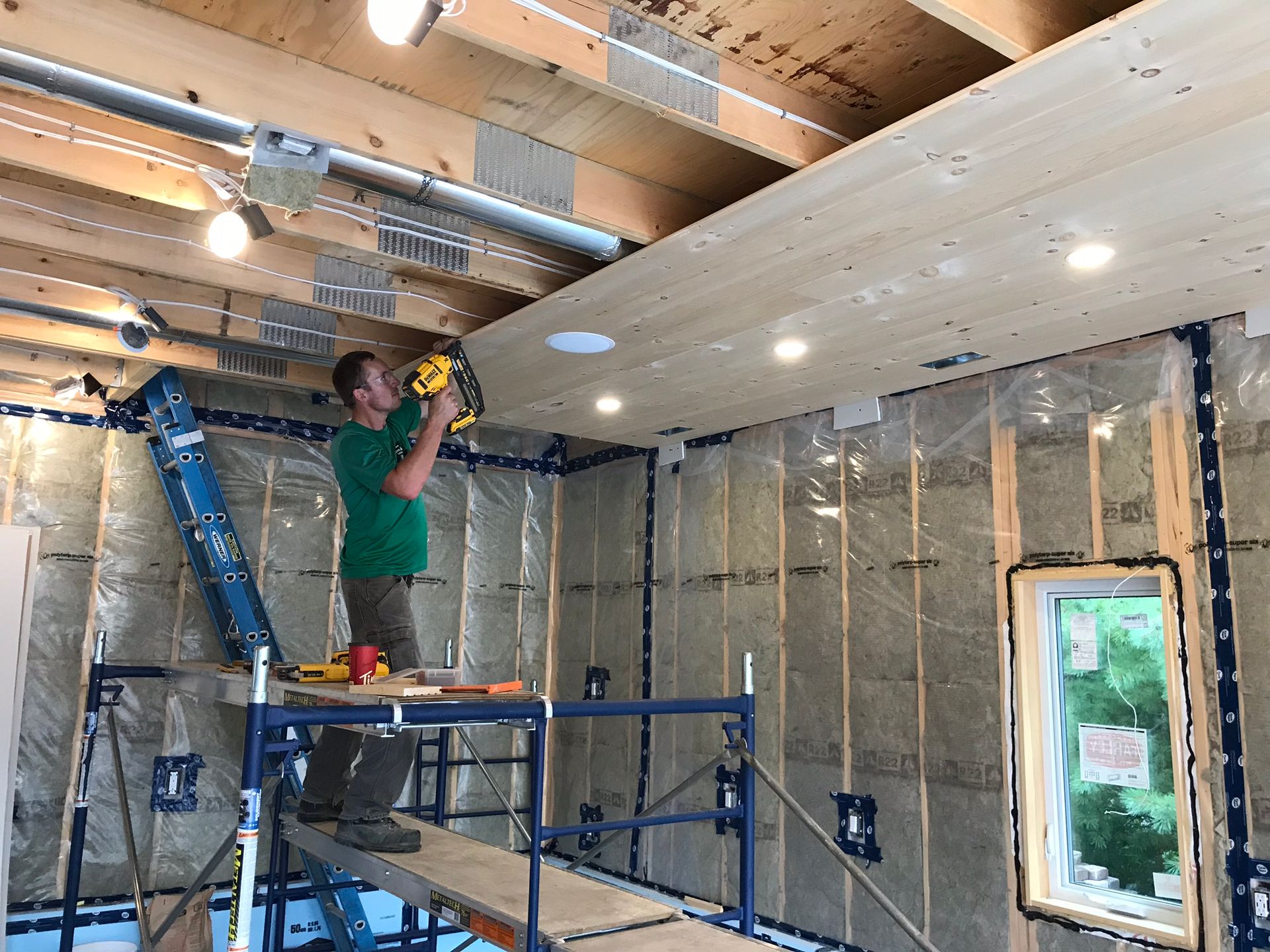 a man is standing on a scaffolding working on a wooden ceiling .