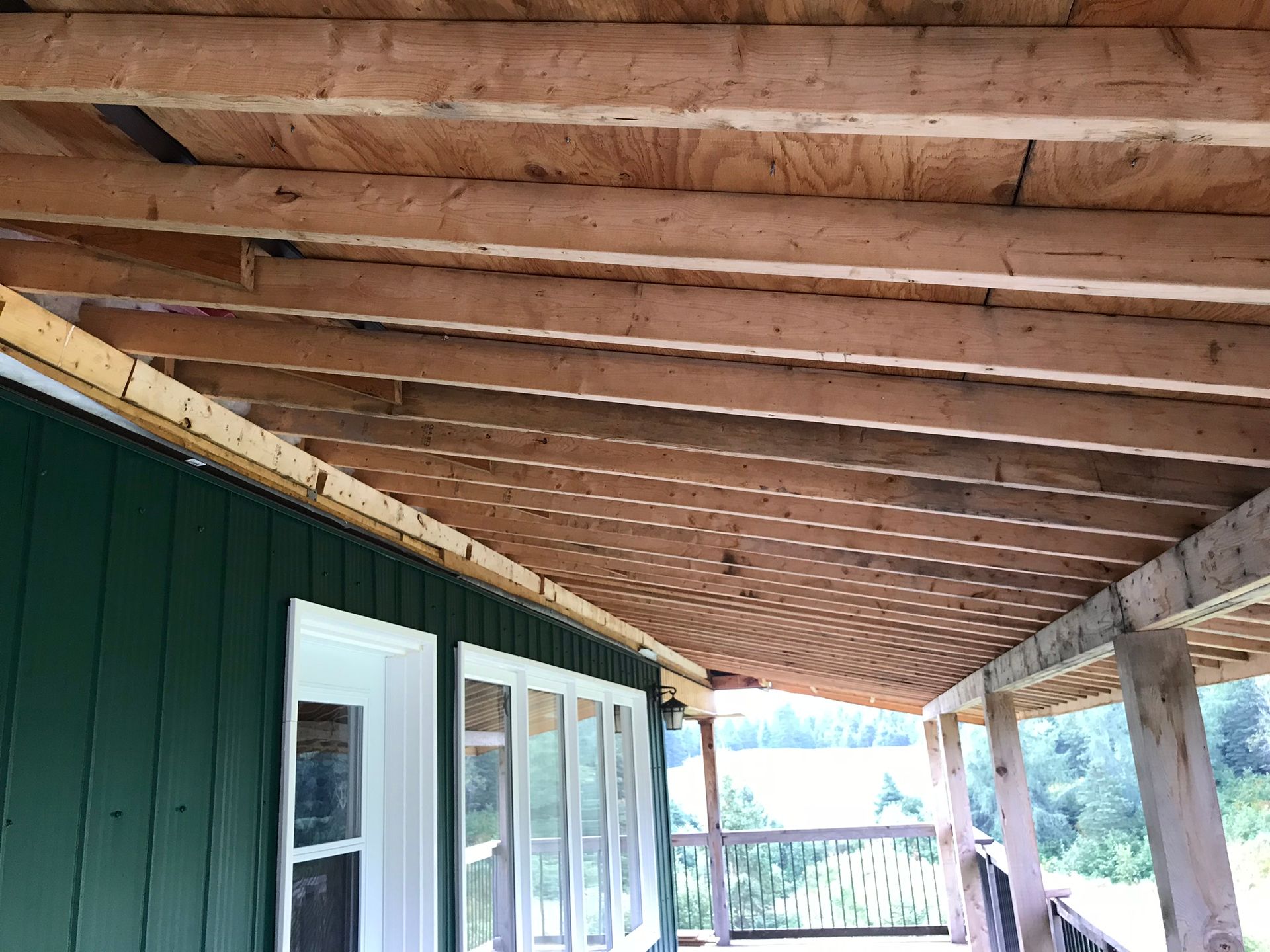 a green house with a porch and a wooden roof .