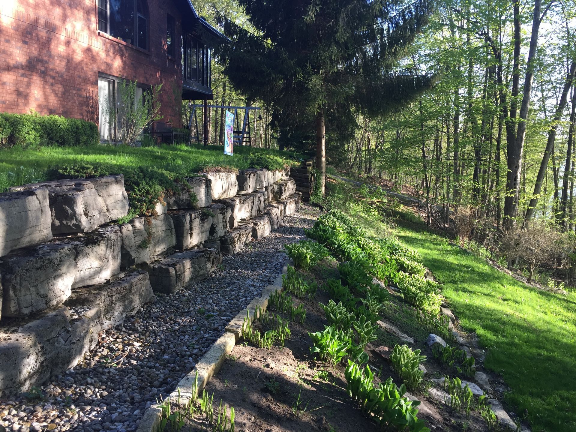 a stone wall is surrounded by grass and trees in front of a house .