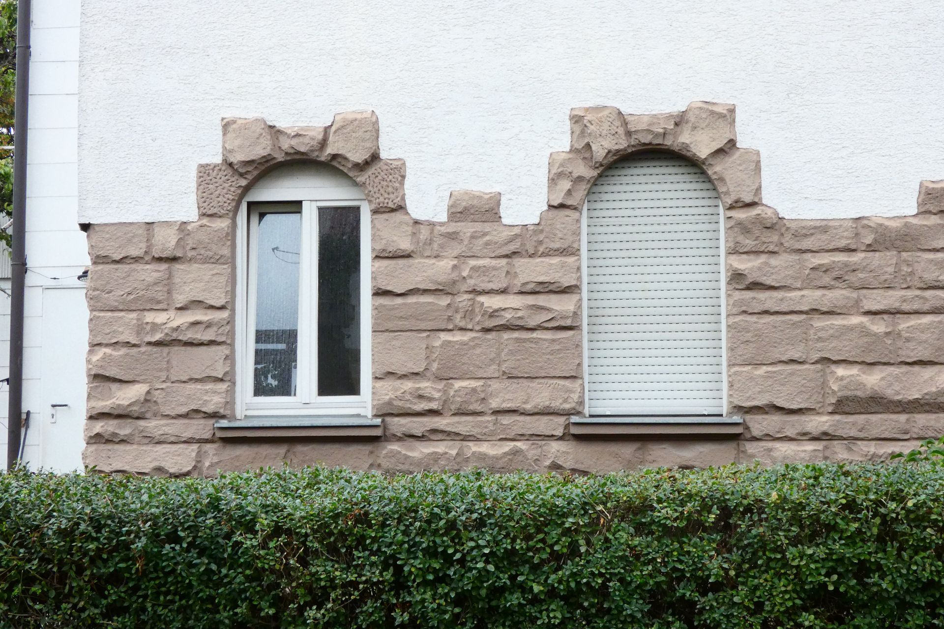 Two windows on a stone wall with shutters on them