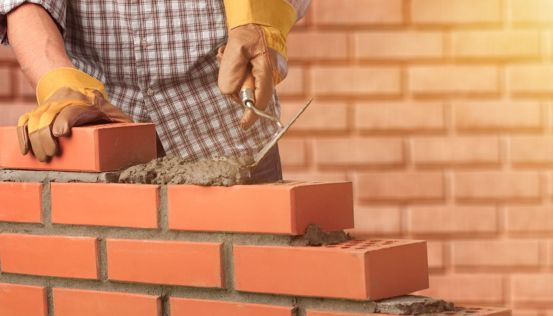 a man is laying bricks on a brick wall .