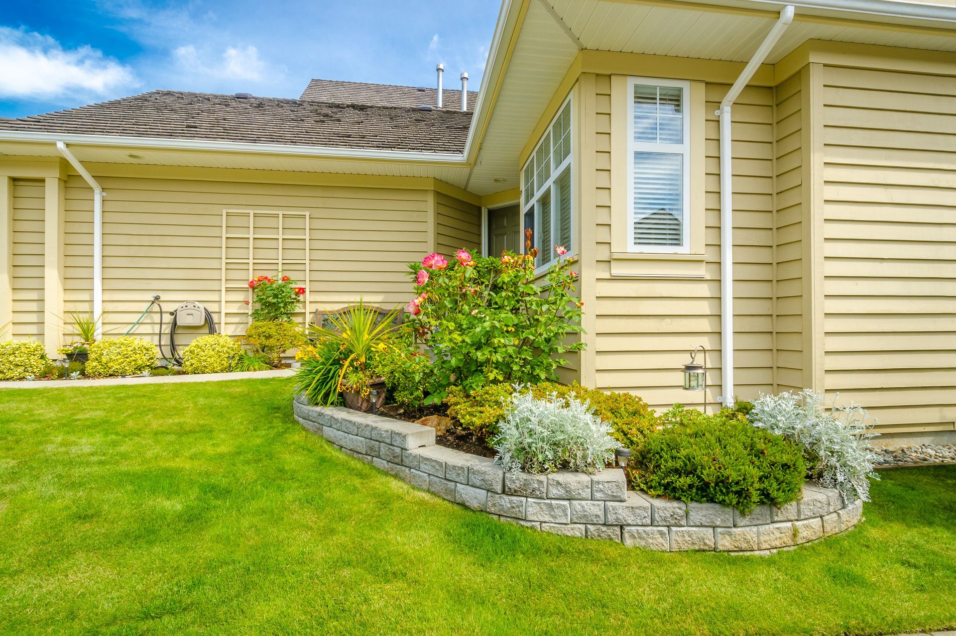 a house with a lush green lawn and a garden in front of it .