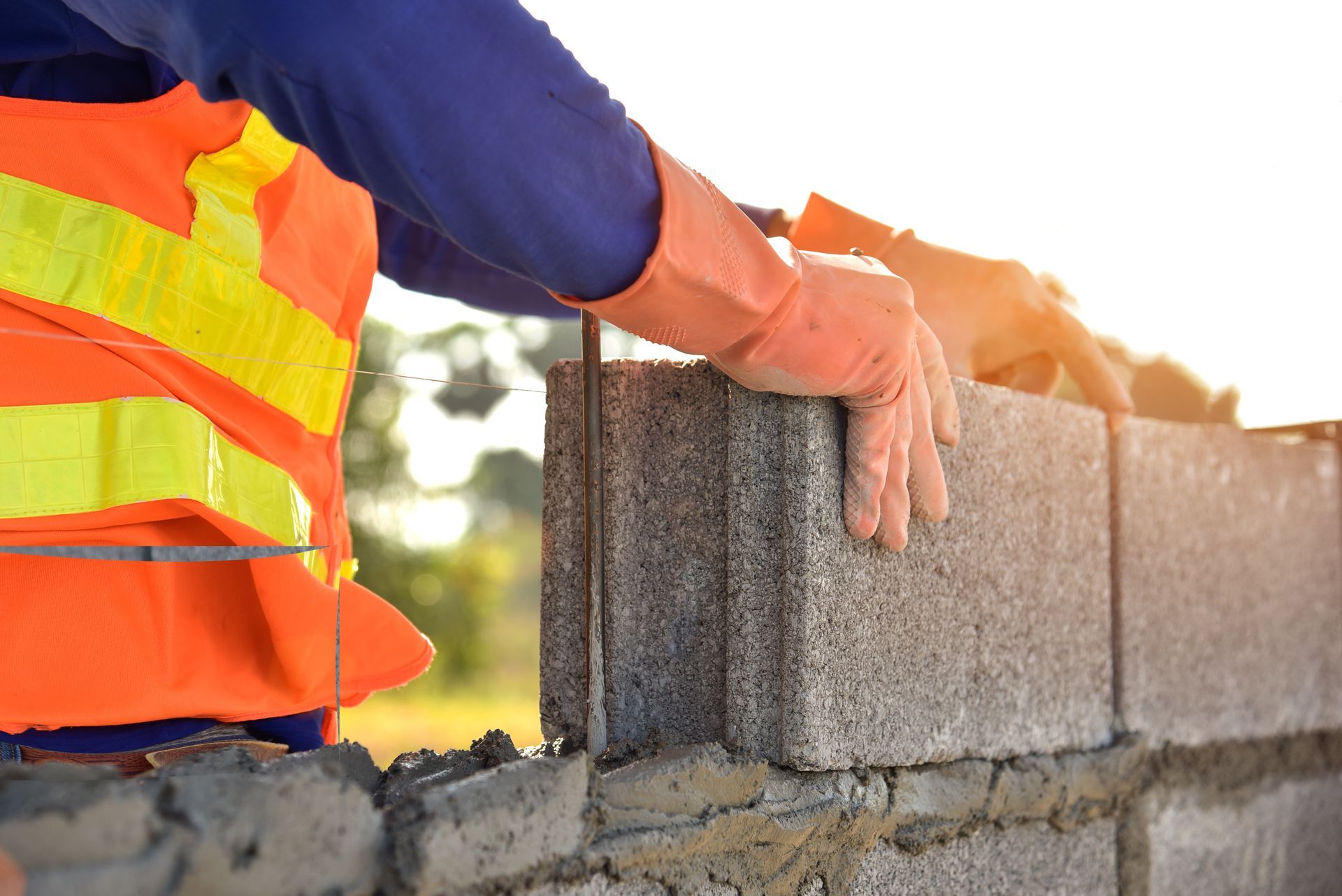 A construction worker is laying bricks on a wall.