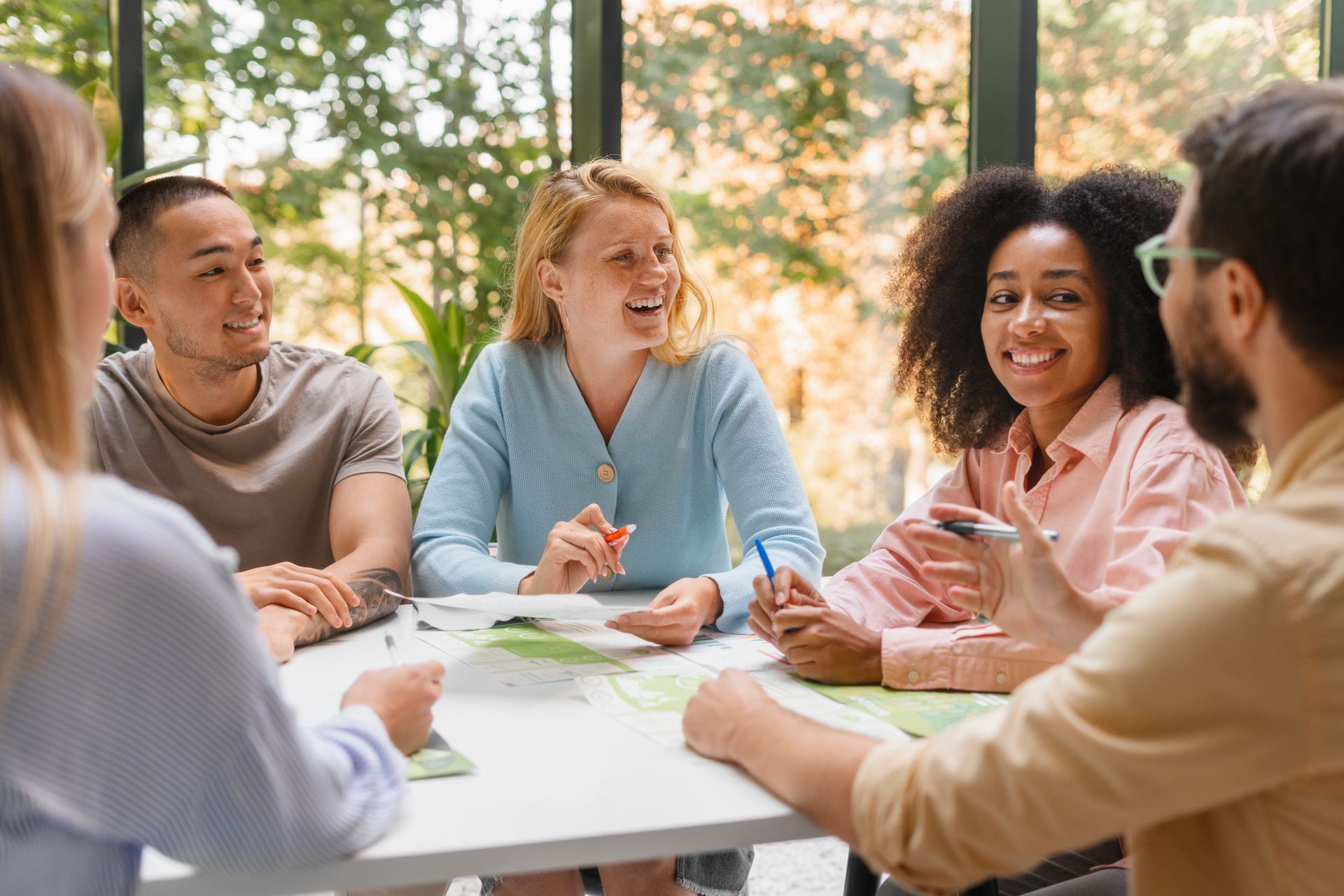 A group of people are sitting around a table having a meeting.