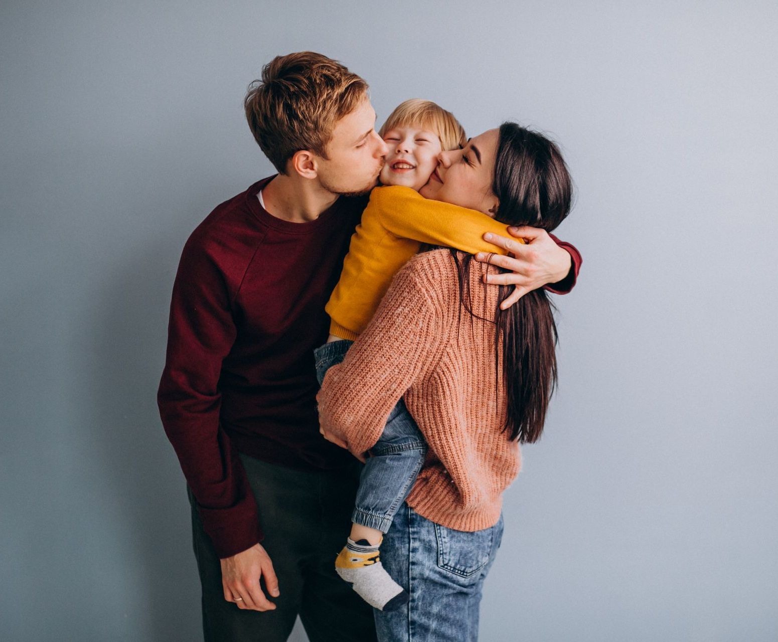 A man is kissing a woman on the cheek while holding a baby.
