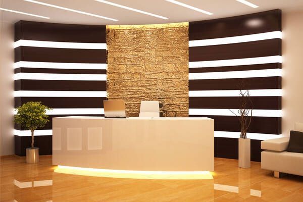 Modern office reception area with a white curved desk and decorative lighting.