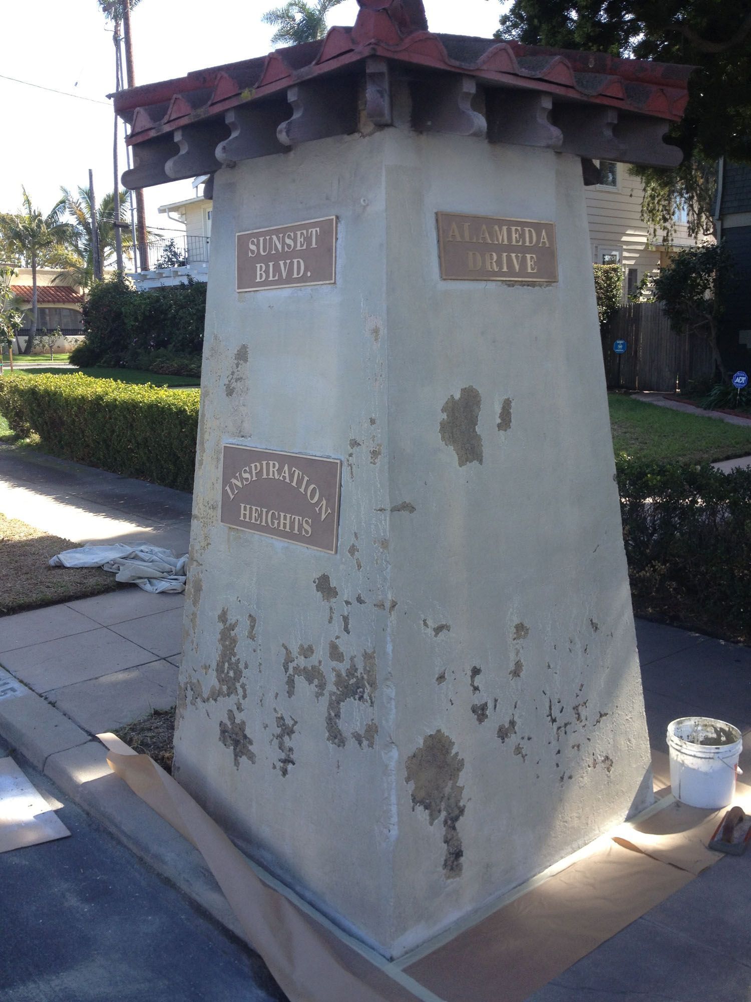 Street address marker with faded text, on a concrete pillar. 
