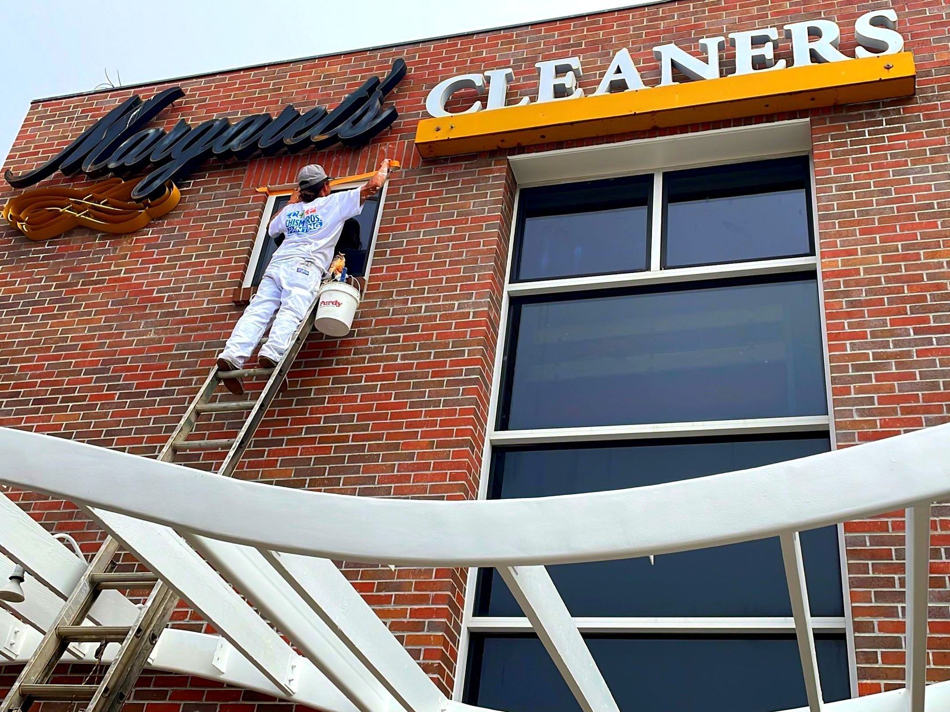 Painter on ladder painting exterior of 
