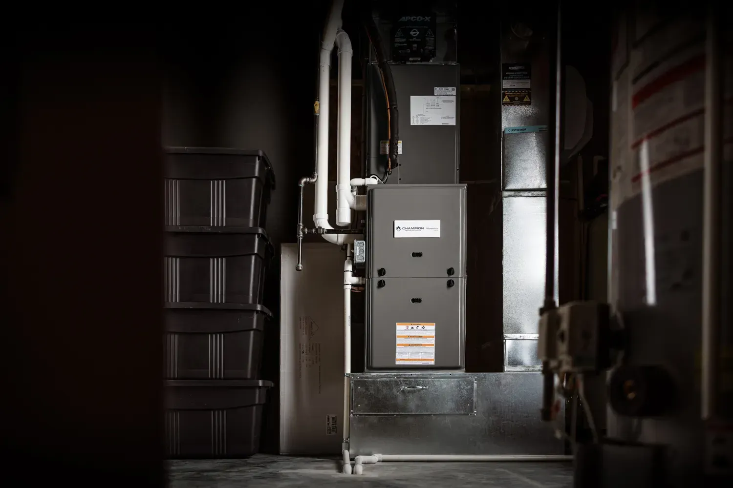 HVAC technician in hard hat inspects furnace controls indoors.