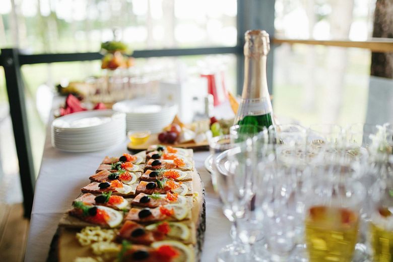 A buffet table with a bottle of champagne and glasses of wine.