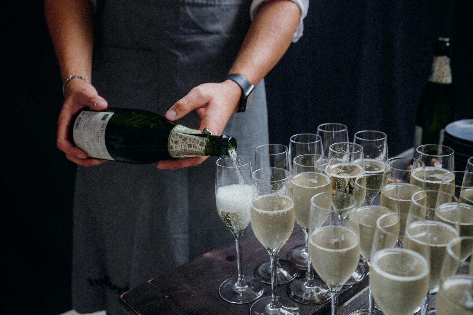 A man is pouring champagne into glasses on a table.