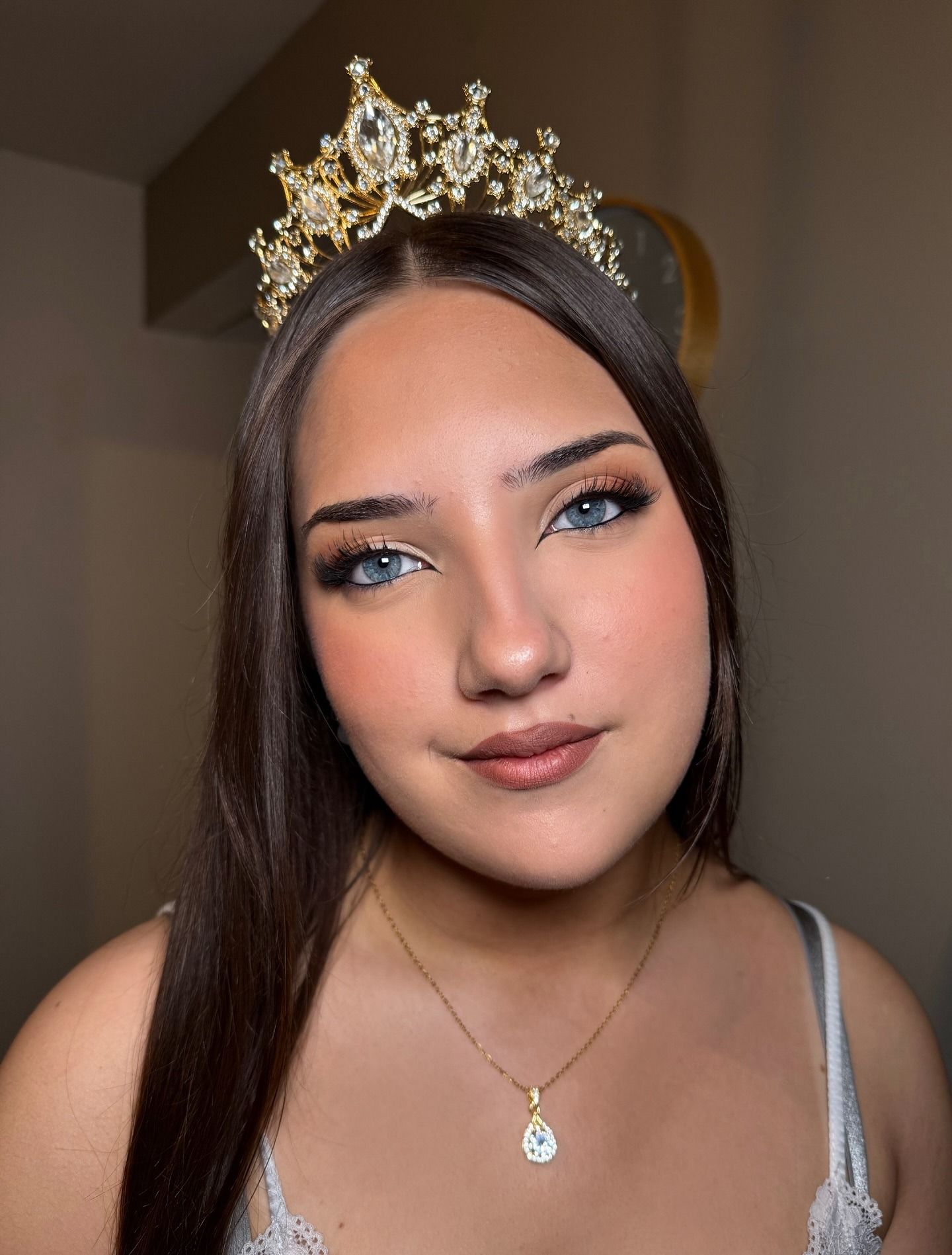 Retrato de una mujer con cabello largo y oscuro, que lleva una corona y un collar de oro