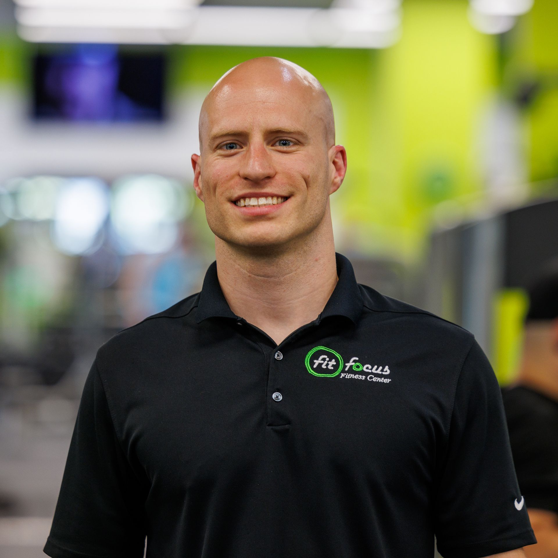 Bald man wearing a black polo shirt with