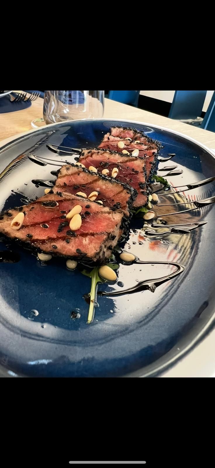 Risotto ai frutti di mare, guarnito con alghe scure, servito su un piatto blu.