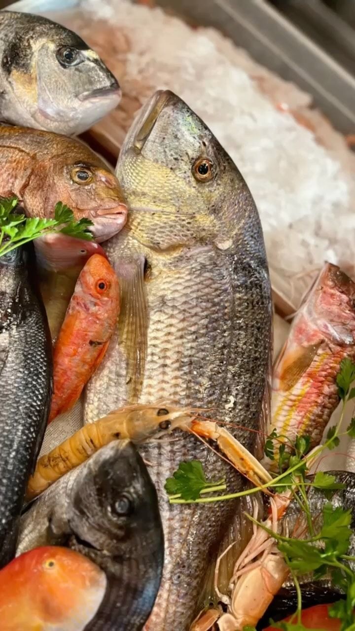 Esposizione di pesce al bancone di un mercato con la scritta