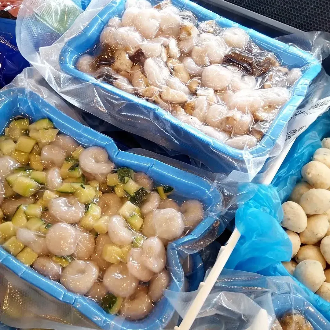 Contenitori di frutti di mare: gamberetti, verdure e altri articoli non identificati.