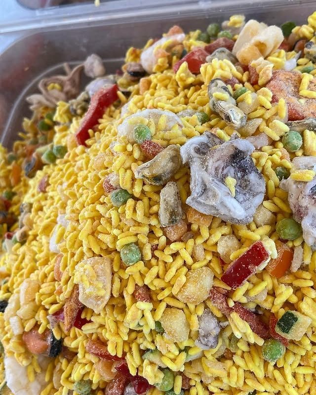 Piatto di riso giallo con frutti di mare e verdure in un vassoio.