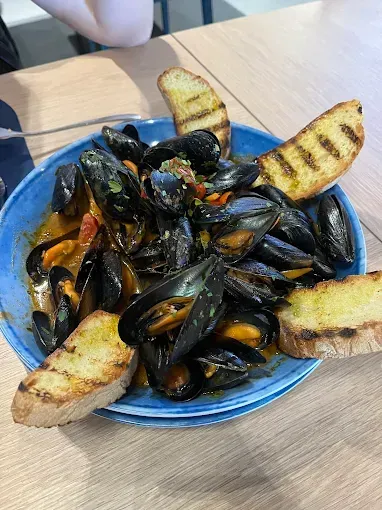 Ciotola di cozze in salsa, servita con pane grigliato.