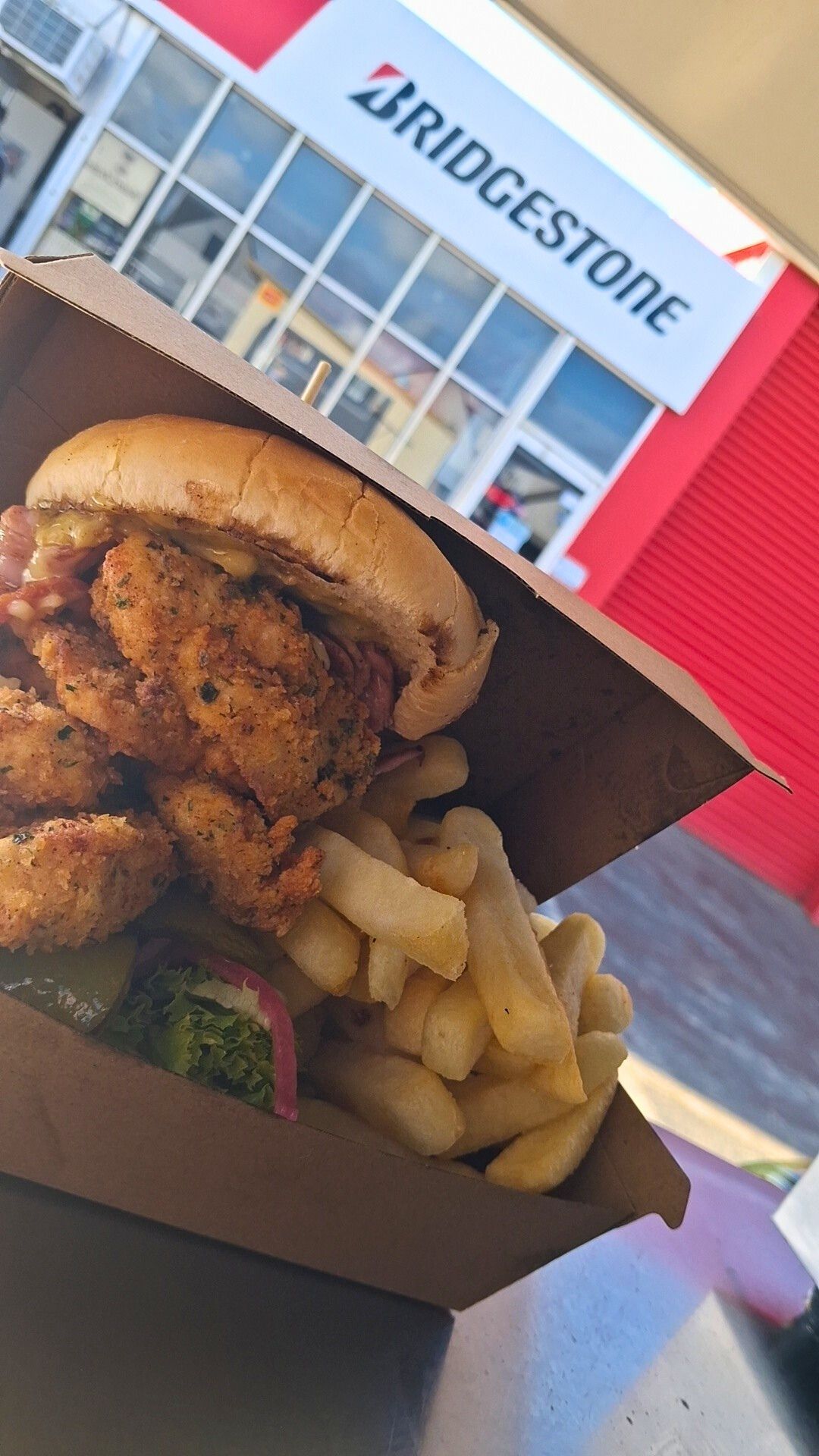 Woman holding a basket of fresh tomatoes, eggplant, and pepper. Outdoors, dog nearby.