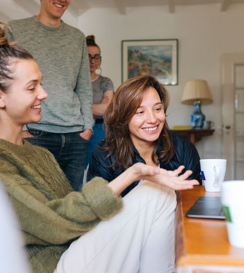 A group of people are sitting around a table and smiling.