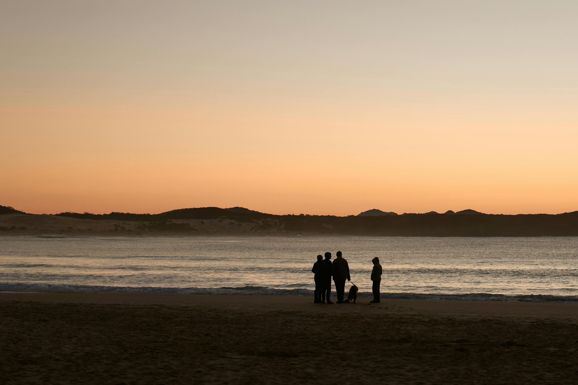 The sun is setting over a sandy beach with a river running through it.