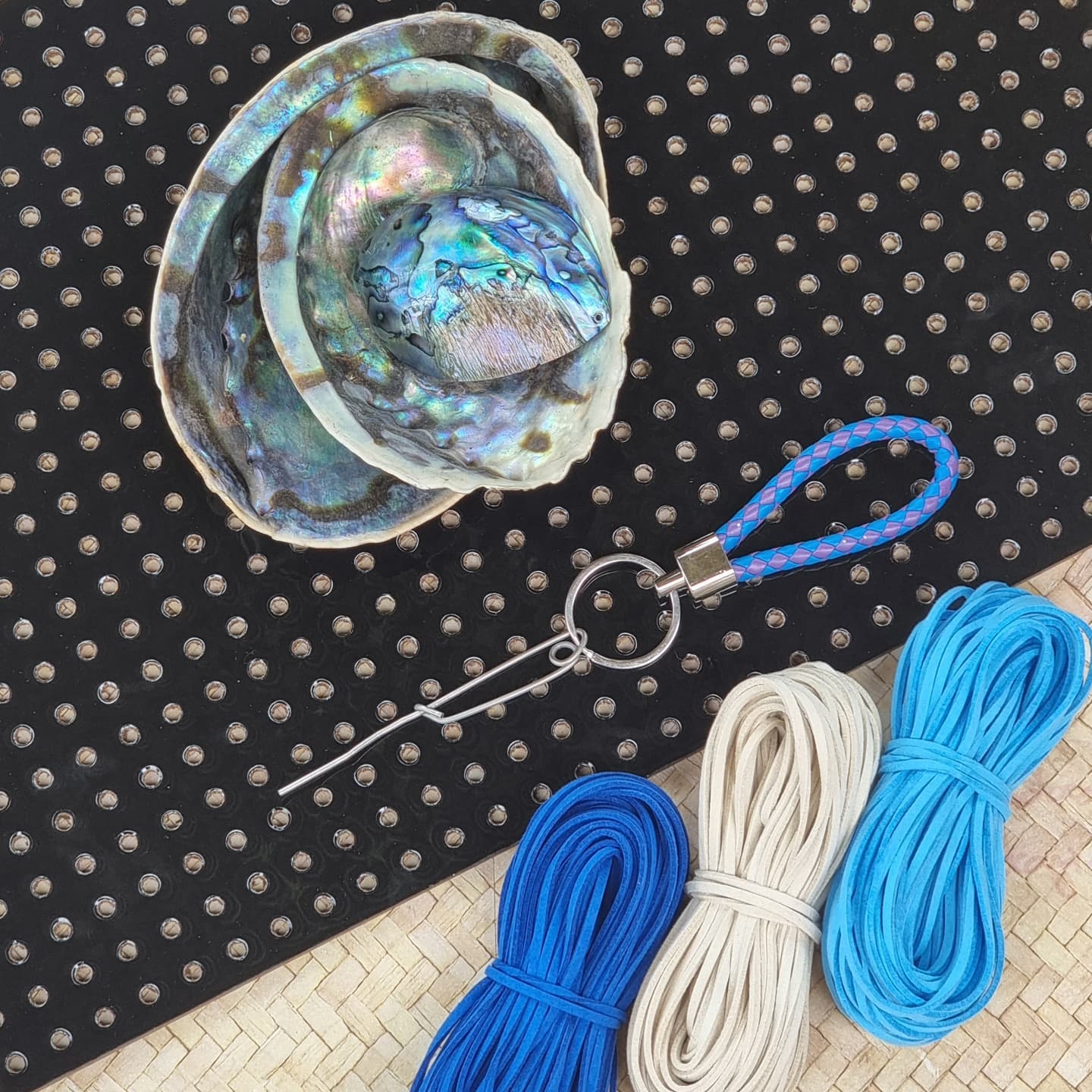 A sea shell is sitting on a polka dot cloth next to a keychain and yarn