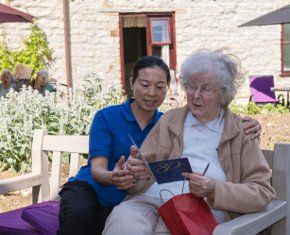 a carer helping an elderly women read a note