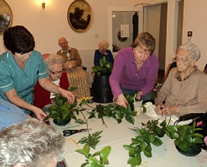 carers assisting elderly people with green leaves decoration