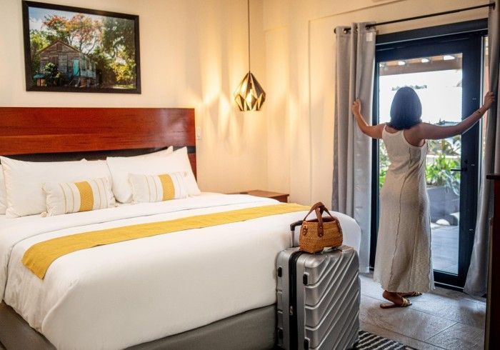 A woman is standing in a hotel room with a suitcase.