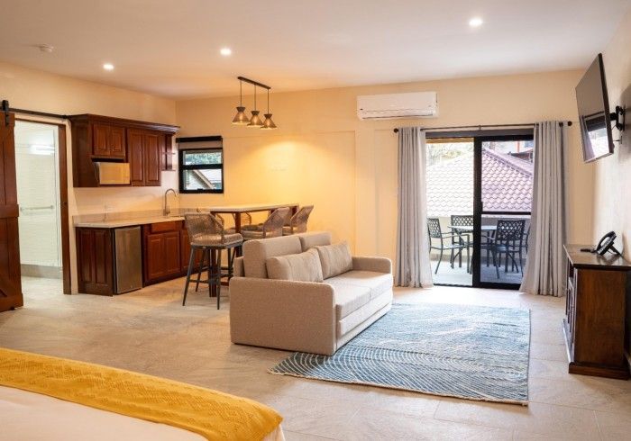 A living room with a couch , television , and sliding glass doors.