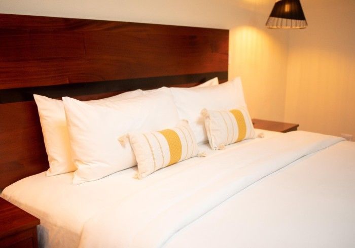 A bed with white sheets and yellow pillows in a hotel room.