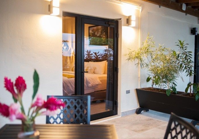 A patio with a table and chairs and a sliding glass door leading to a bedroom.