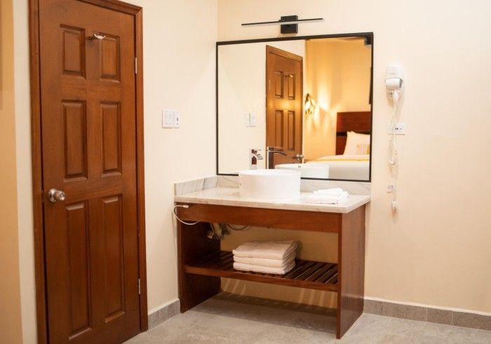 A bathroom in a hotel room with a sink and a mirror.