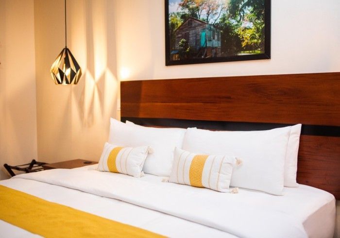 A bed with white sheets and yellow pillows in a hotel room.