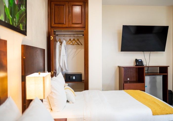 A hotel room with a bed , television , safe and closet.