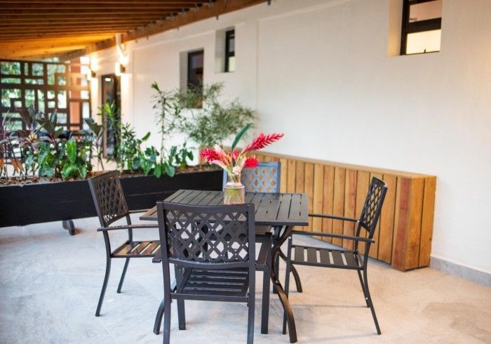 A table and chairs with a vase of flowers on it.